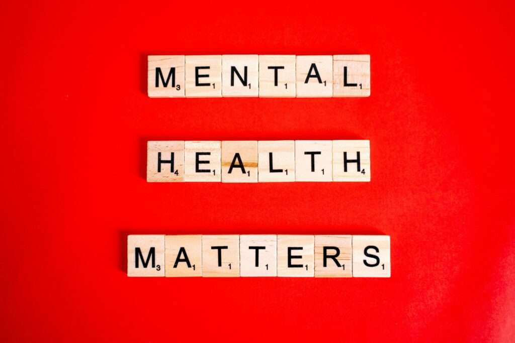 Wooden tiles spelling 'Mental Health Matters' on a vivid red background.